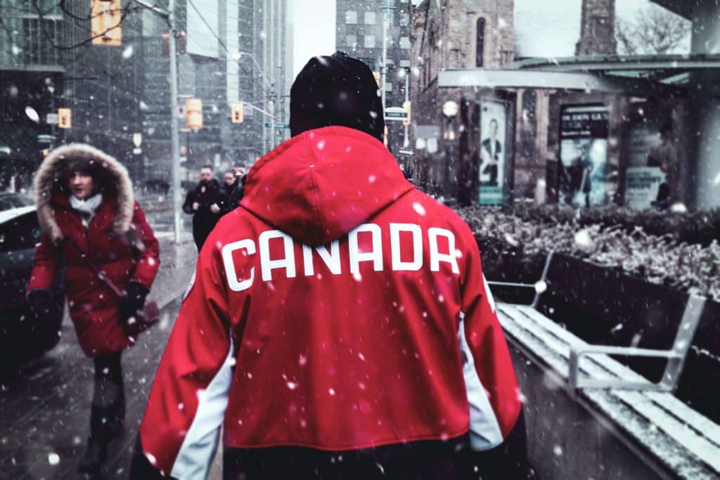 Toronto em um dia de inverno, com neve caindo, e pessoas corajosas na rua enfrentando o frio.